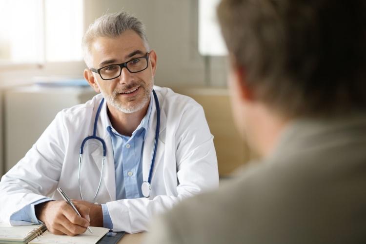 Smiling doctor looks at patient who wants to quit drinking