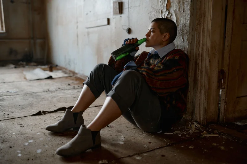 Depressed young addict drinks a beer in an abandoned building