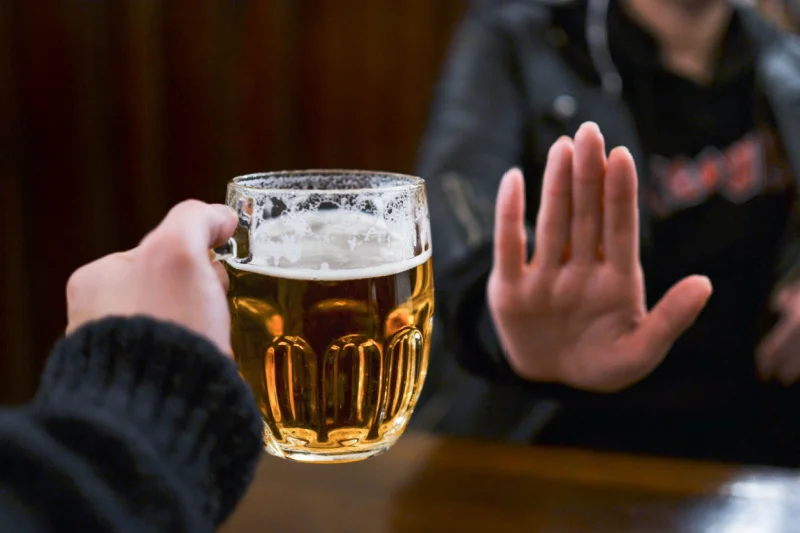 Outstretched hand refuses mug of beer