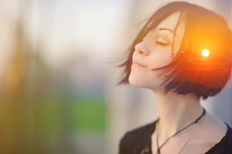 Picture of sunset overlaid on the head of a content young woman