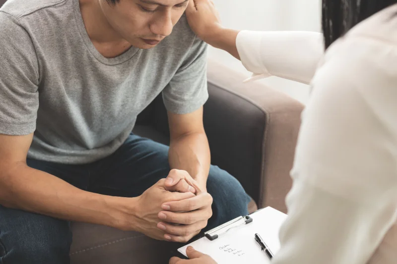 Therapist puts a comforting hand on depressed young man