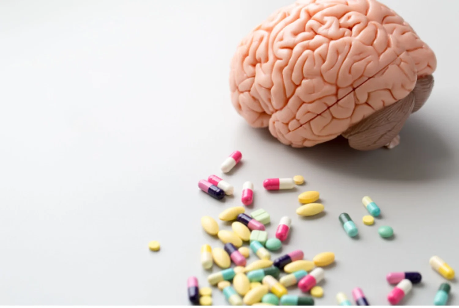Model of a human brain next to a variety of pills