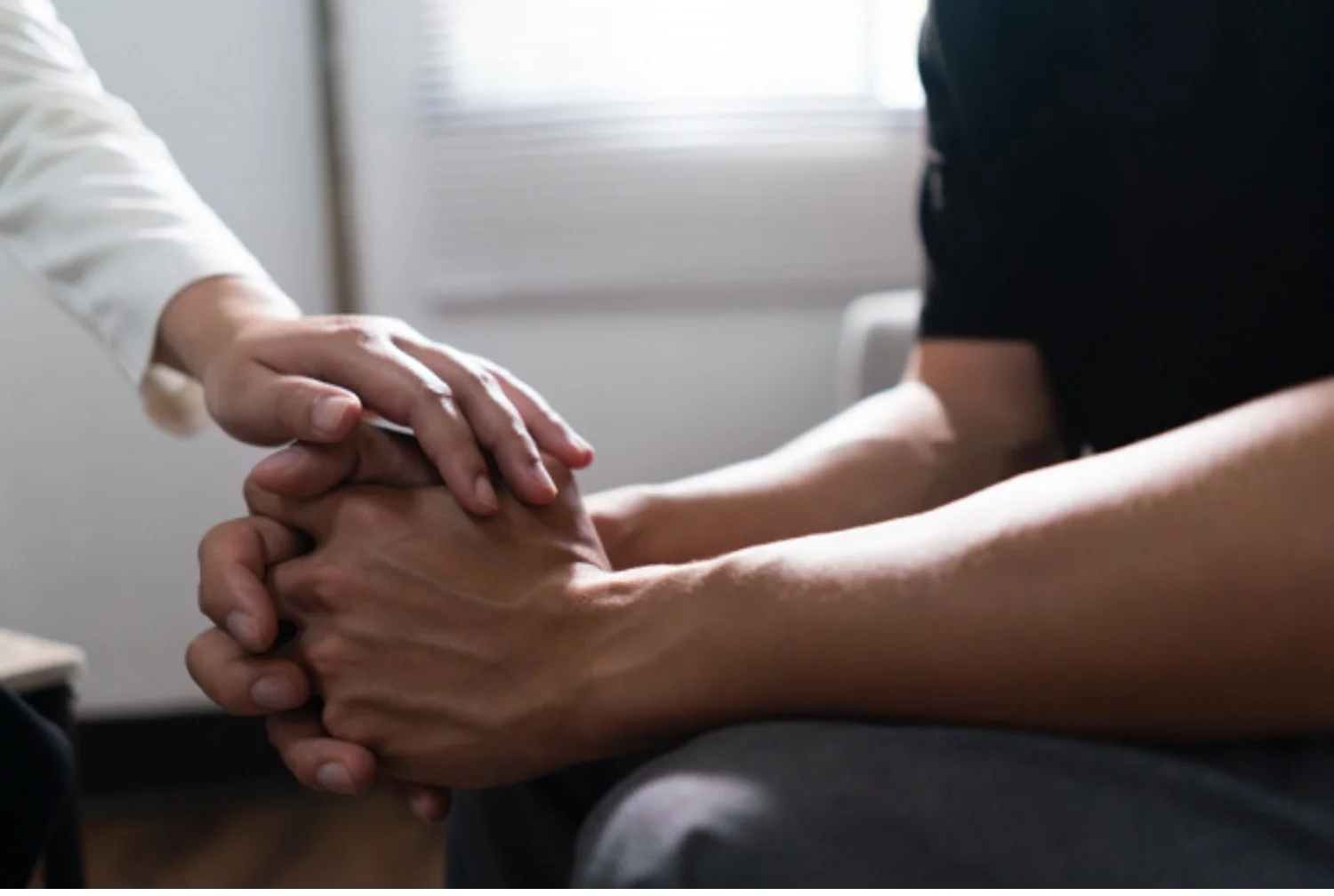Therapist puts a comforting hand on the hands of a mental health patient