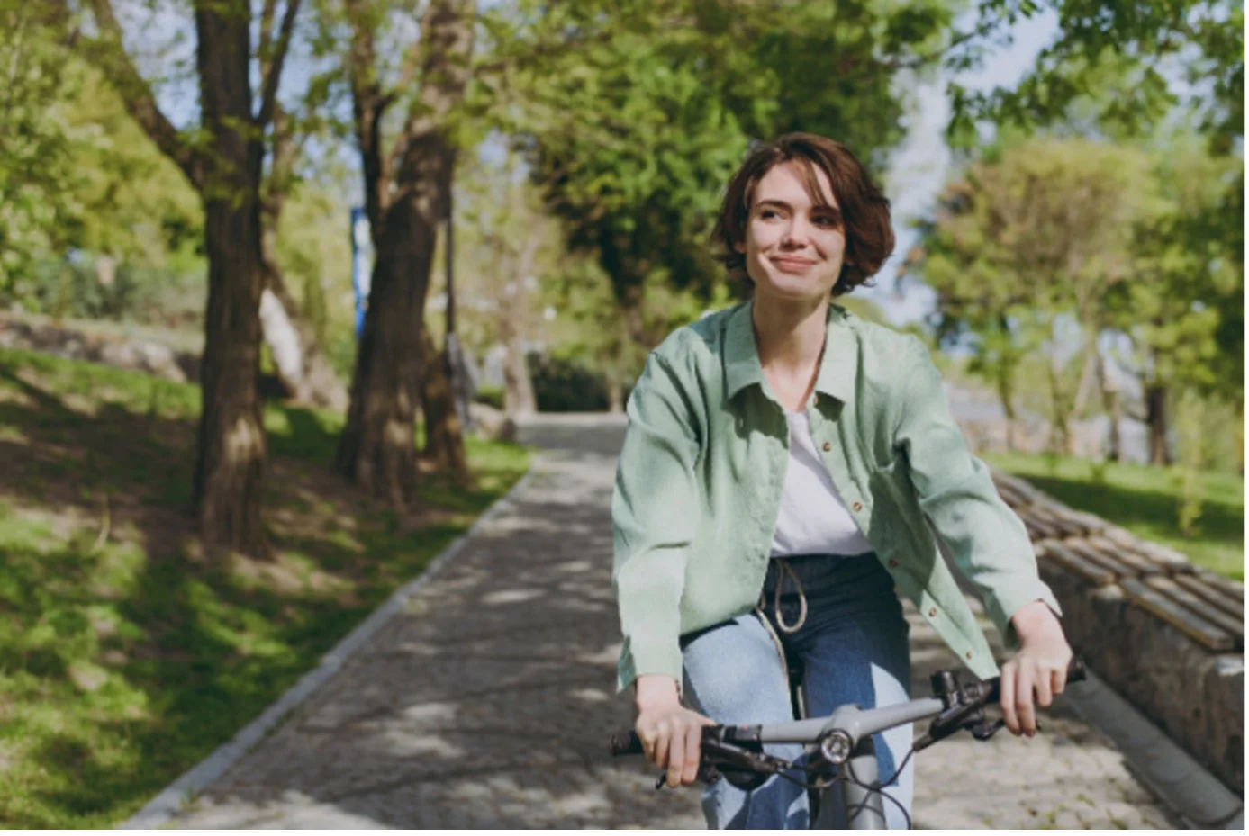 Woman smiles while riding a bike along a tree-lined path