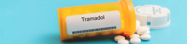 Bottle of tramadol tipped on its side with pills spilling out