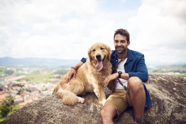 Man recovered from kratom addiction smiles as he sits with his golden retriever in a scenic location