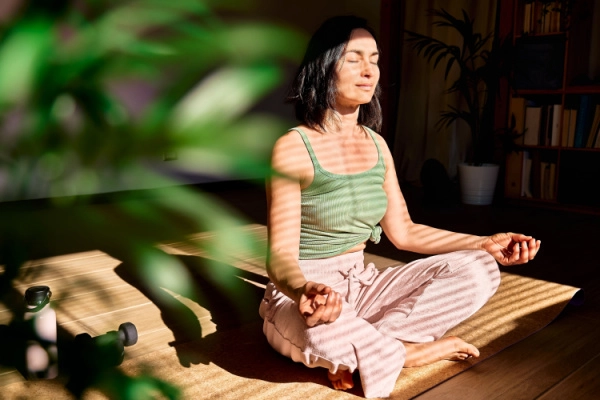 Peaceful woman meditates in a ray of sunlight
