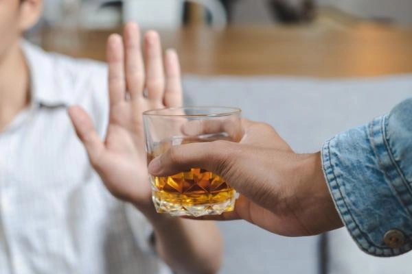 Recovering alcohol addict refuses a glass of whiskey