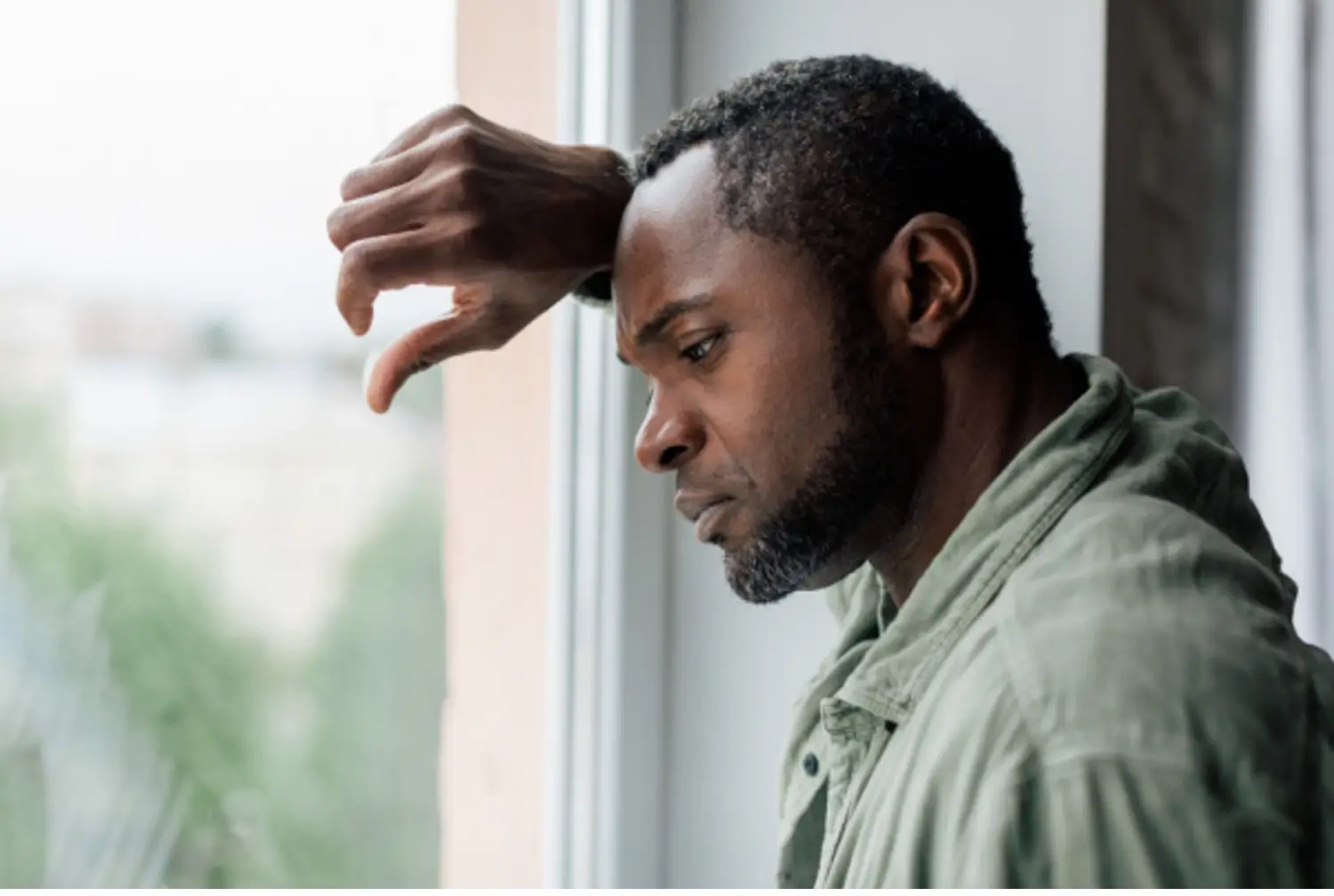 Man going through Paxil withdrawal looks out window with depressed look on his face