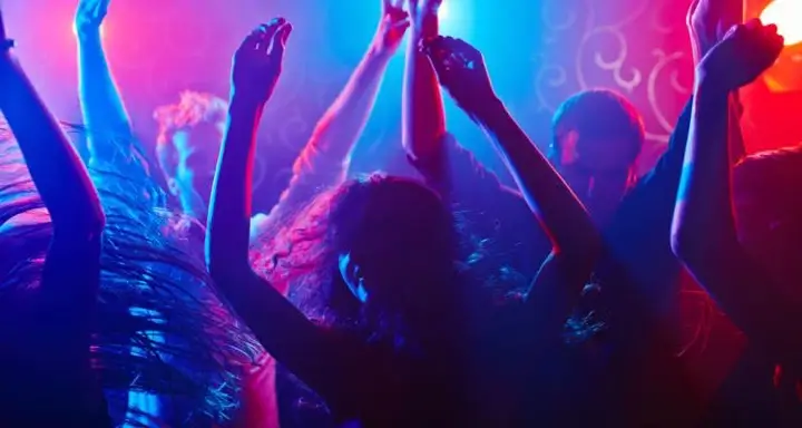People dancing at a club with their arms in the air