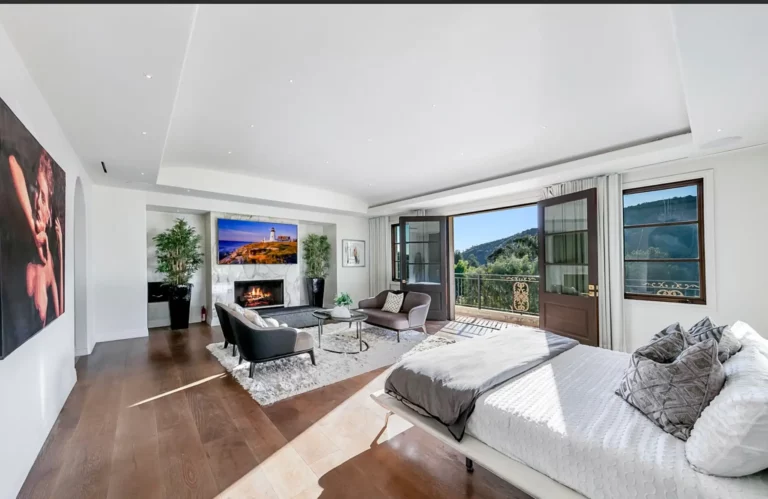 Bedroom at Legacy Healing' drug and alcohol rehab in Los Angeles, complete with bed, sitting area, fireplace, canyon views, and calming modern decor