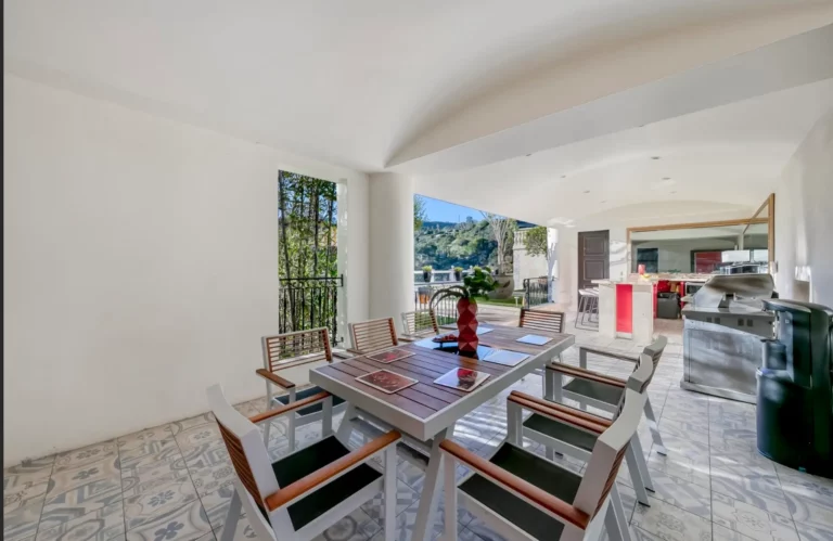Sun room eating area with dining table and open access to outdoor terrace overlooking the Hollywood Hills