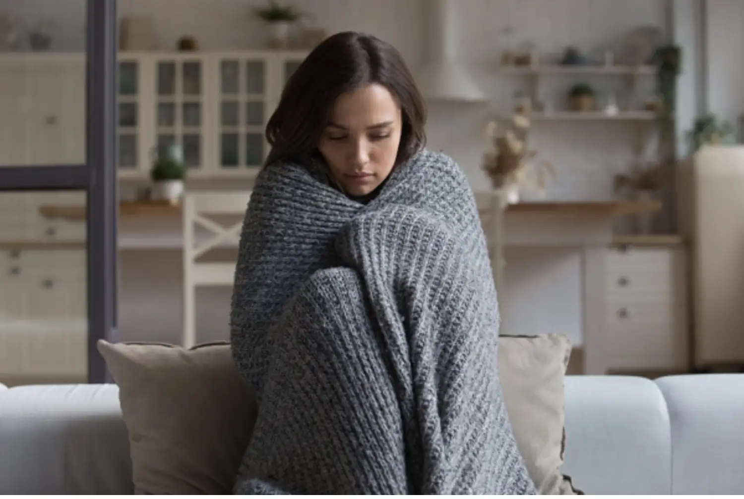 Woman going through Paxil withdrawal wrapped in a blanket with sad look on her face