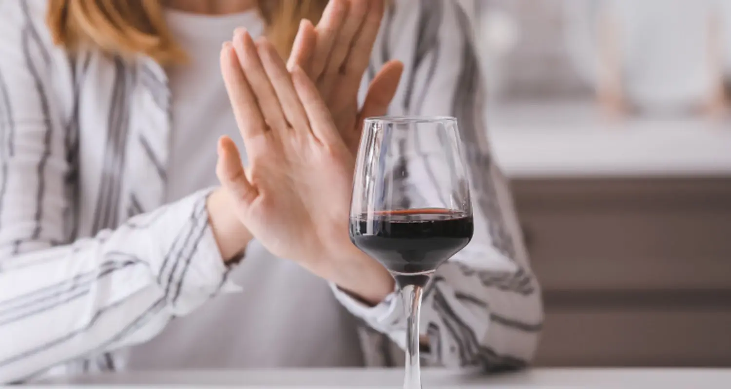 Woman crosses hands to refuse a glass of red wine
