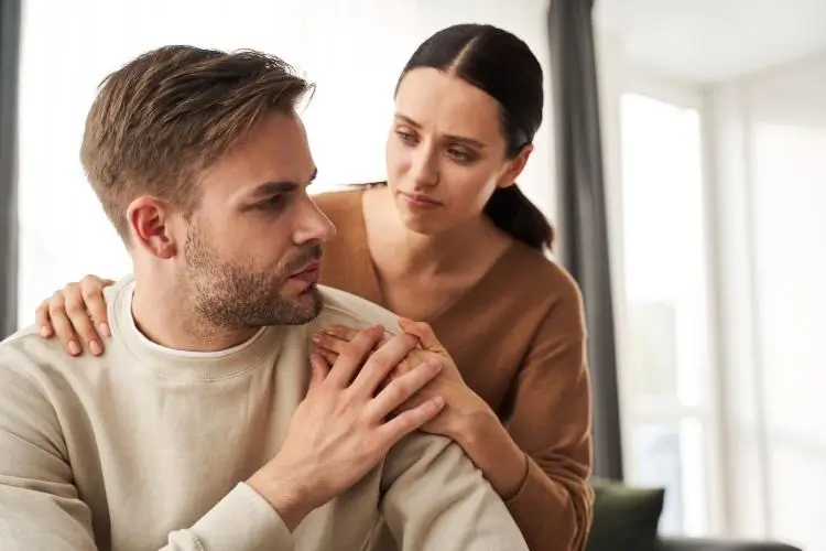 Wife puts reassuring hand on husband’s shoulder during discussion of his drinking