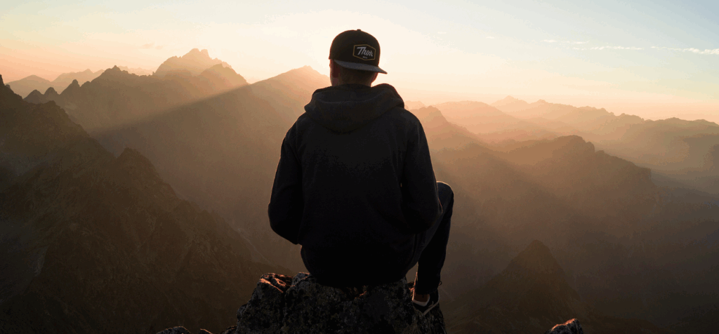 individual's silhouette as they face a mountain range, letting go of the past and forgiving themselves in recovery