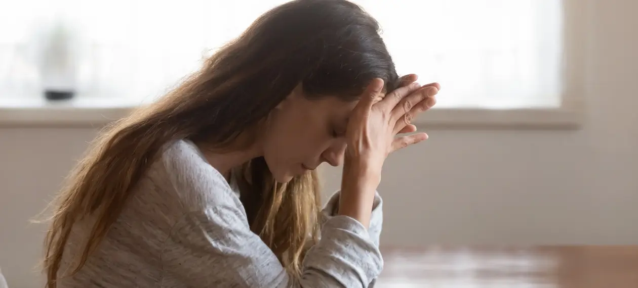 An realistic photo depicting the concept of substance use disorder, showing a woman at a table struggling with SUD and relapse.