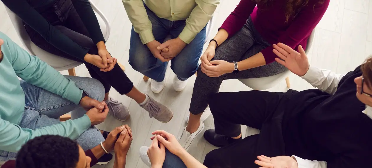 One of the key components of an effective addiction treatment plan in therapy, illustrated in a real photo of a group therapy session for addicts in recovery. 