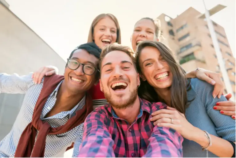 Group of happy young adults smiling outdoors, symbolizing community, connection, and life after recovery at a luxury addiction treatment center in Los Angeles, California.