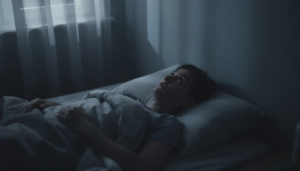A person lies awake in bed at night, staring at the ceiling in a dimly lit room, illustrating the struggle with alcohol detox insomnia, a common alcohol withdrawal symptom and the accompanying sleep disturbances that can disrupt sleep patterns during early recovery from alcohol use disorder. The scene conveys a sense of restlessness and difficulty falling asleep, highlighting the challenges of managing withdrawal symptoms.